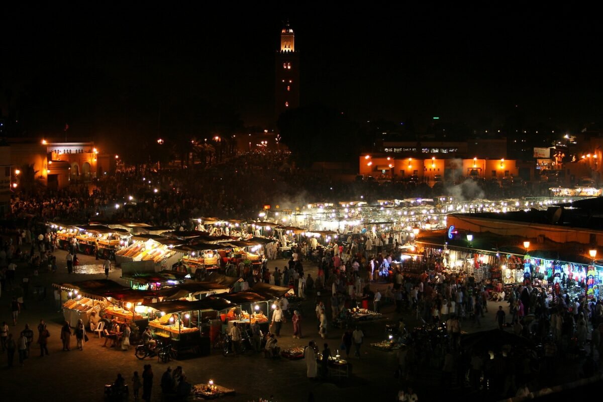 Stands de restauration de Jemaa el-Fna la nuit avec le minaret de la Koutoubia à Marrakech