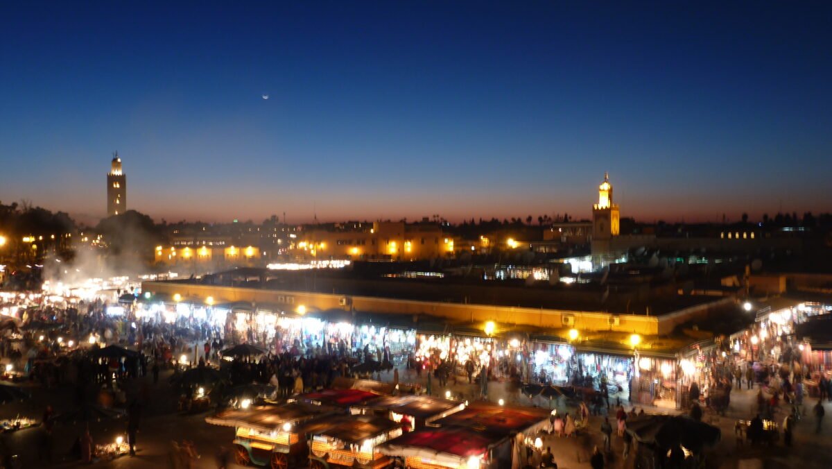 Food stalls spreading across Jemaa el-Fna at dusk, seen from a rooftop terrace