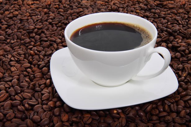 A cup of black coffee (café noir) in a saucer surrounded by coffee beans