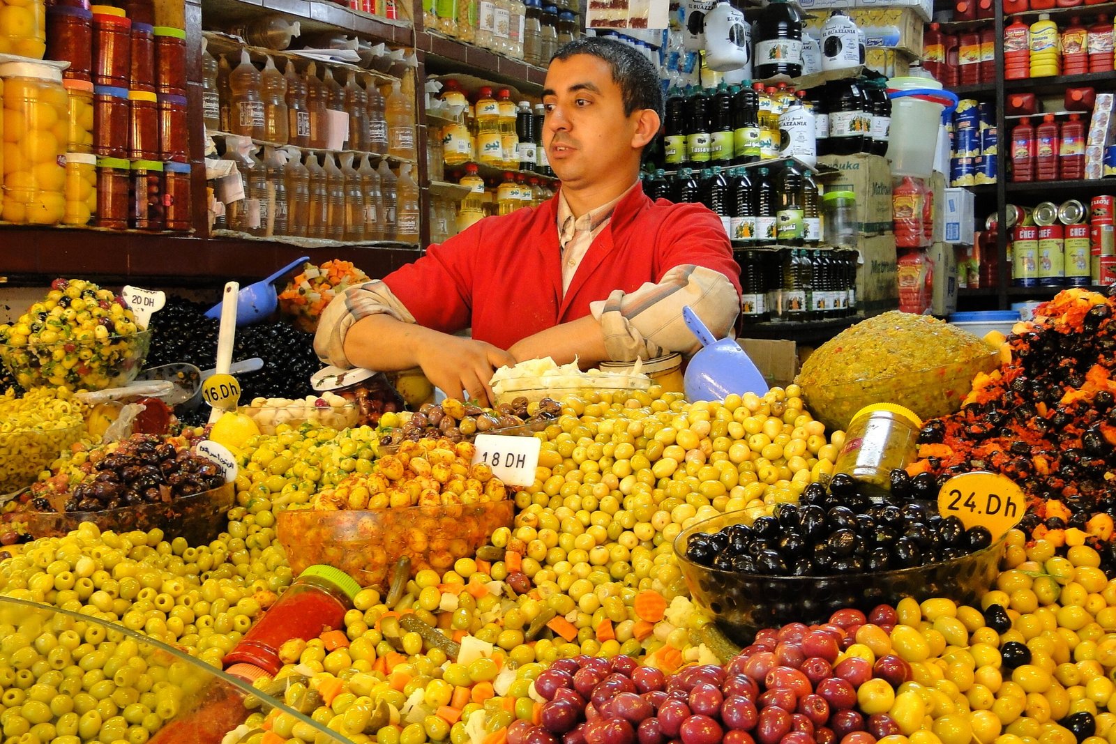 An olive seller at a northern Moroccan market with mounds of olives