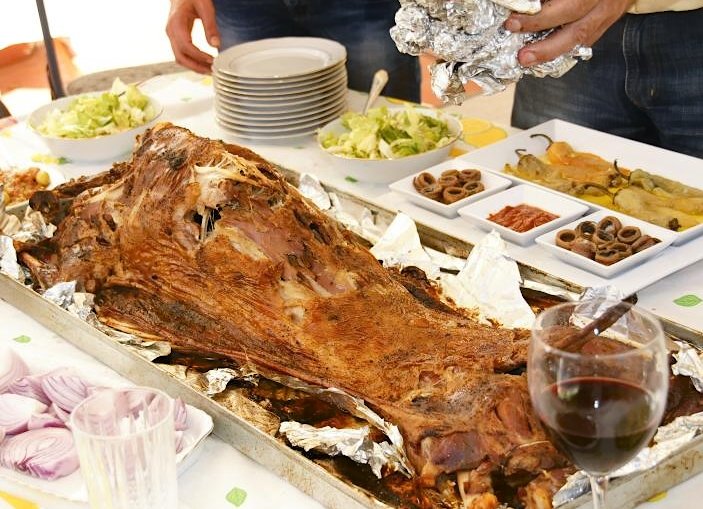 A whole slow-roasted mechoui lamb being carved at a festive table in Morocco