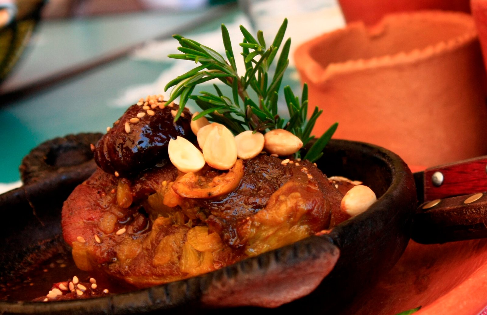 Meat tagine with caramelized quinces, almonds and prunes in a black clay tajine dish