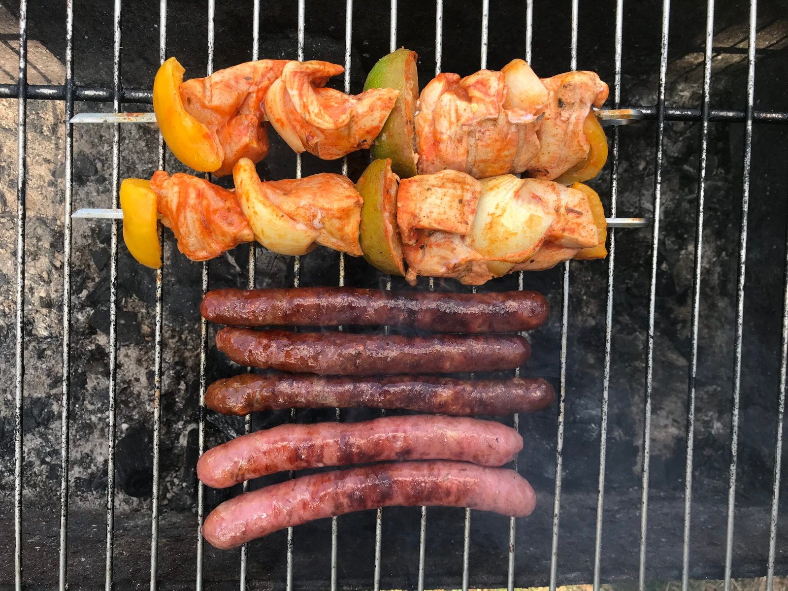 Brochettes and merguez sausages grilling over charcoal