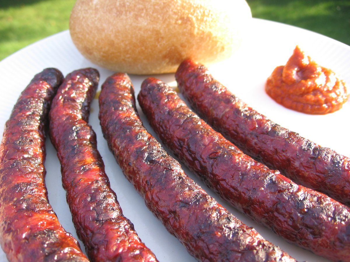 Merguez sausages grilling over charcoal
