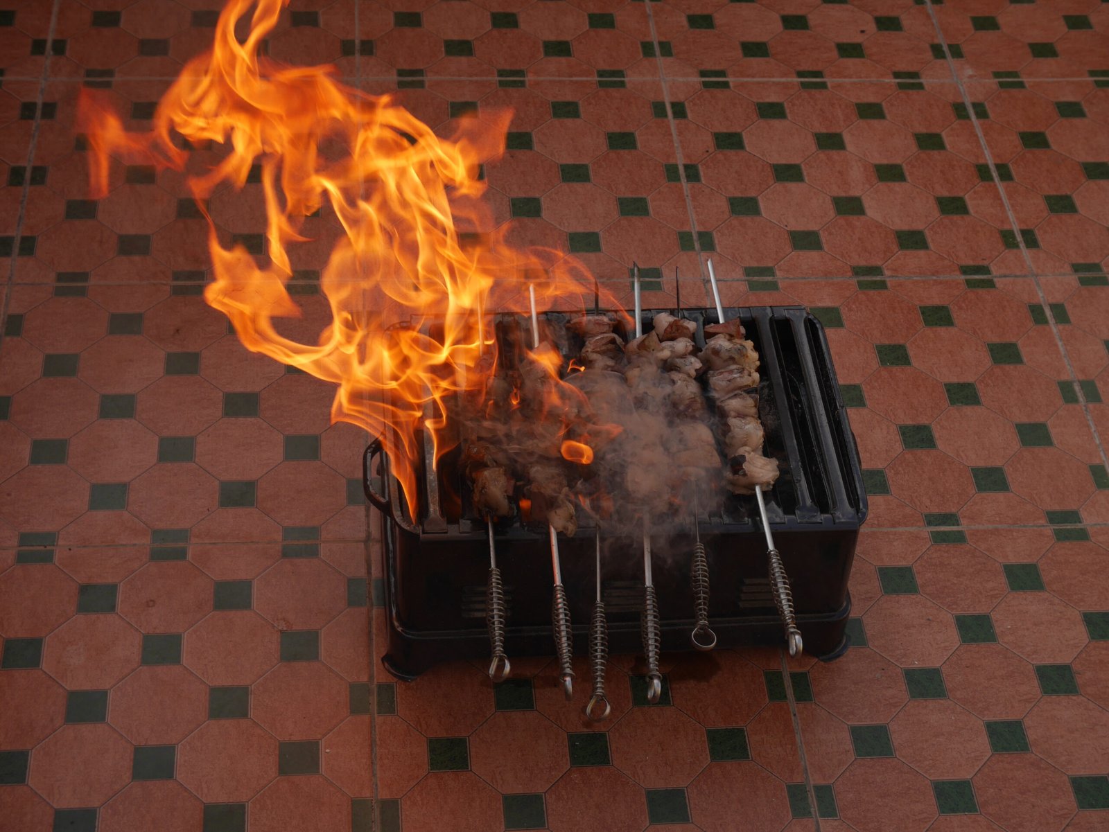 Brochettes grilling over open flames on a portable grill