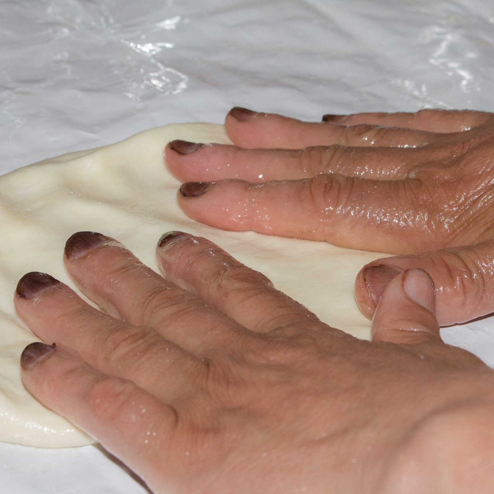 Moroccan woman preparing msemen flatbread on a hot griddle