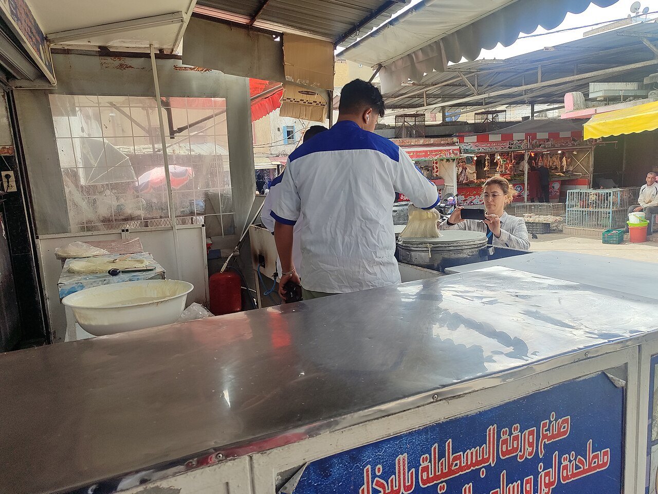 Vendor brushing thin warka pastry sheets onto a hot griddle at a souk in Casablanca, Morocco