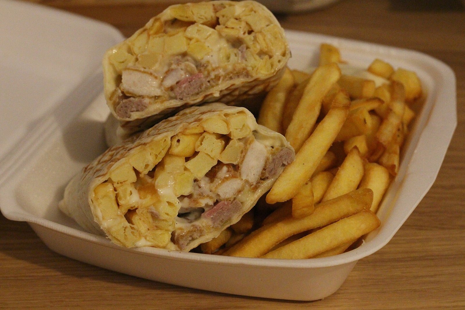 French tacos cut in half, showing meat, fries and cheese sauce inside