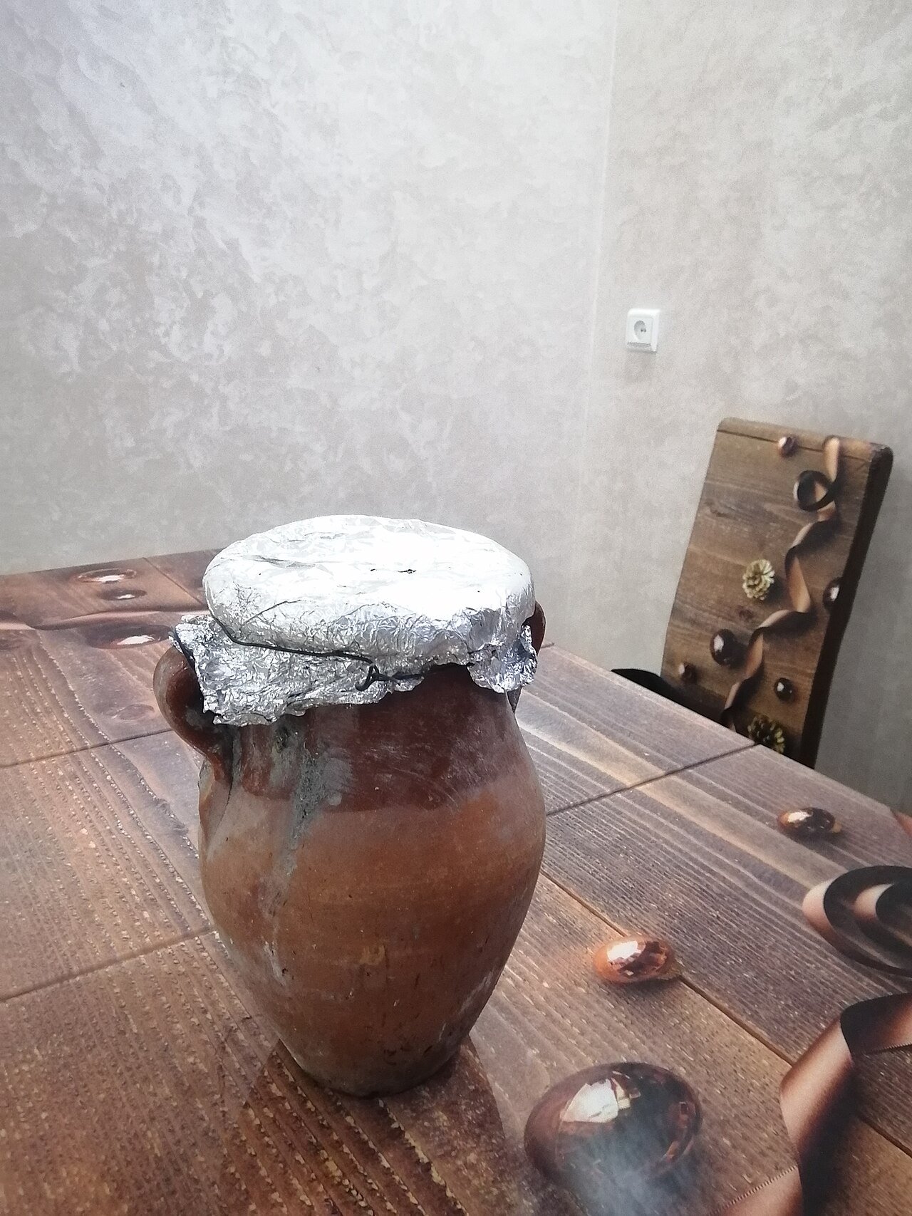 Gros plan d'une urne d'argile de tanjia scellée avec du papier aluminium sur une table