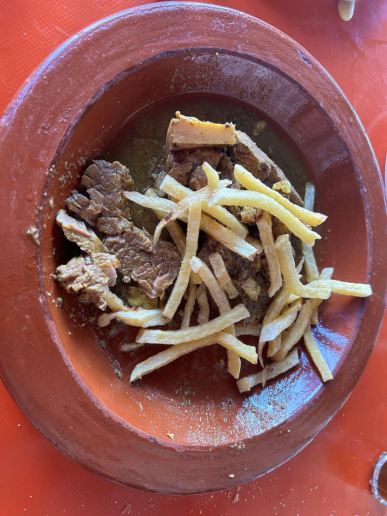 Tanjia servie avec des frites dans l'urne d'argile