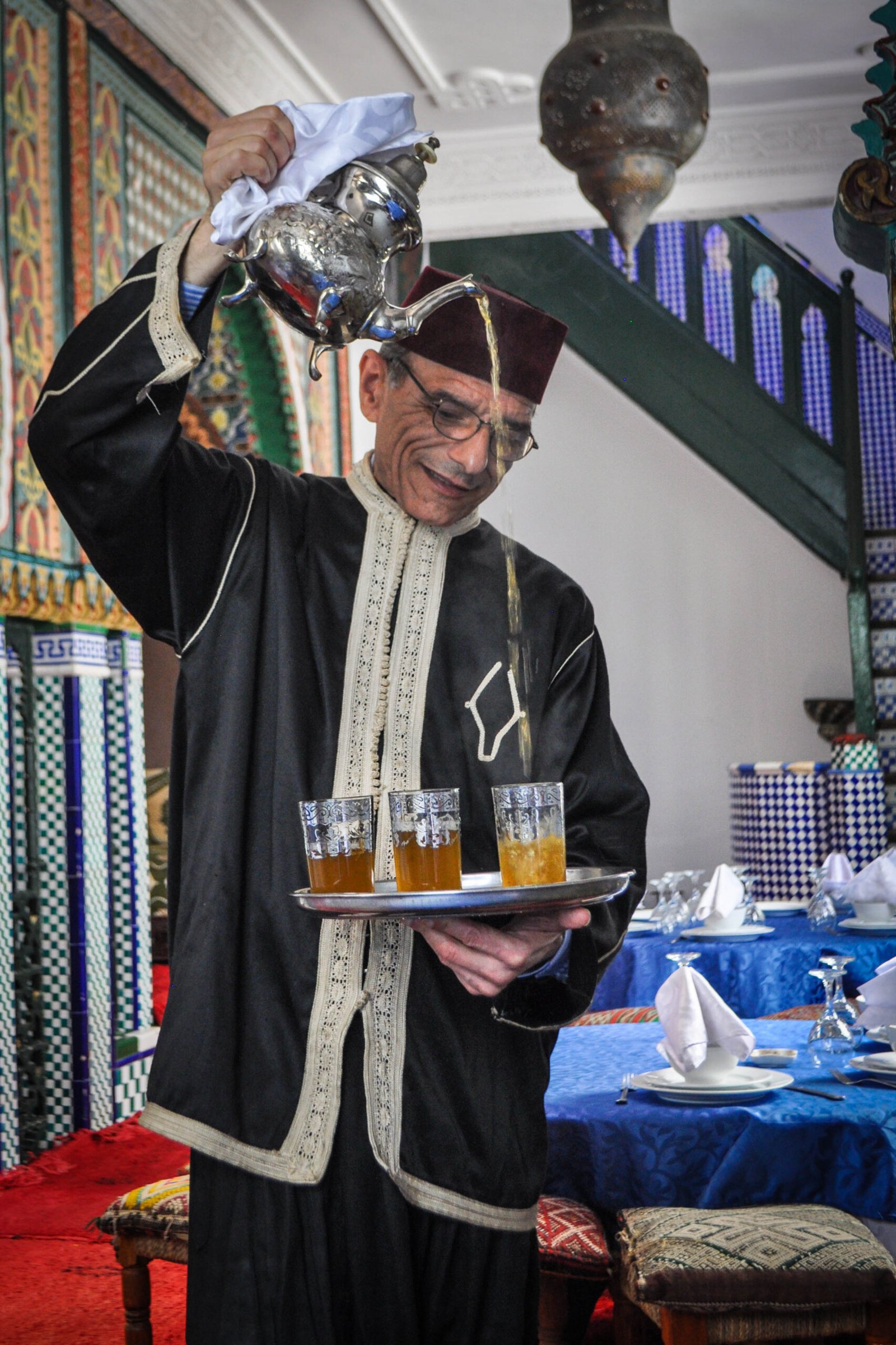 A Moroccan waiter in traditional dress serving mint tea in Tangier