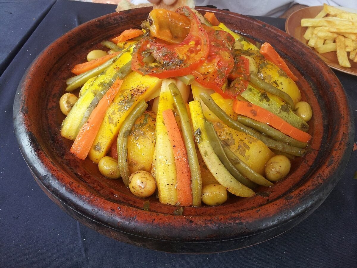 Moroccan vegetable tagine with carrots, zucchini, green beans, tomatoes and olives served in a clay tagine dish